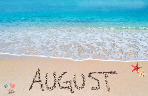 august written on a tropical beach