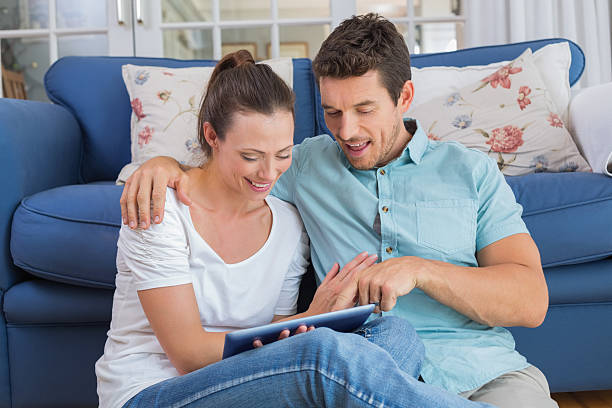 istock Happy couple using digital tablet in living room 466694520