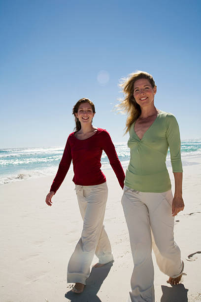 istock Mother and daughter walking on beach hand in hand 466695428