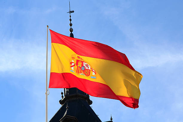istock Spanish flag waving in the wind against a blue sky 466697233