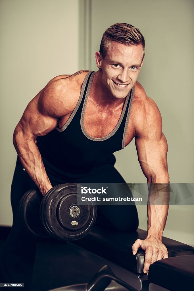 Hnadsome young man working out with dumbbells in fitness Hnadsome young man working out with dumbbells in fitness -  power training 2015 Stock Photo