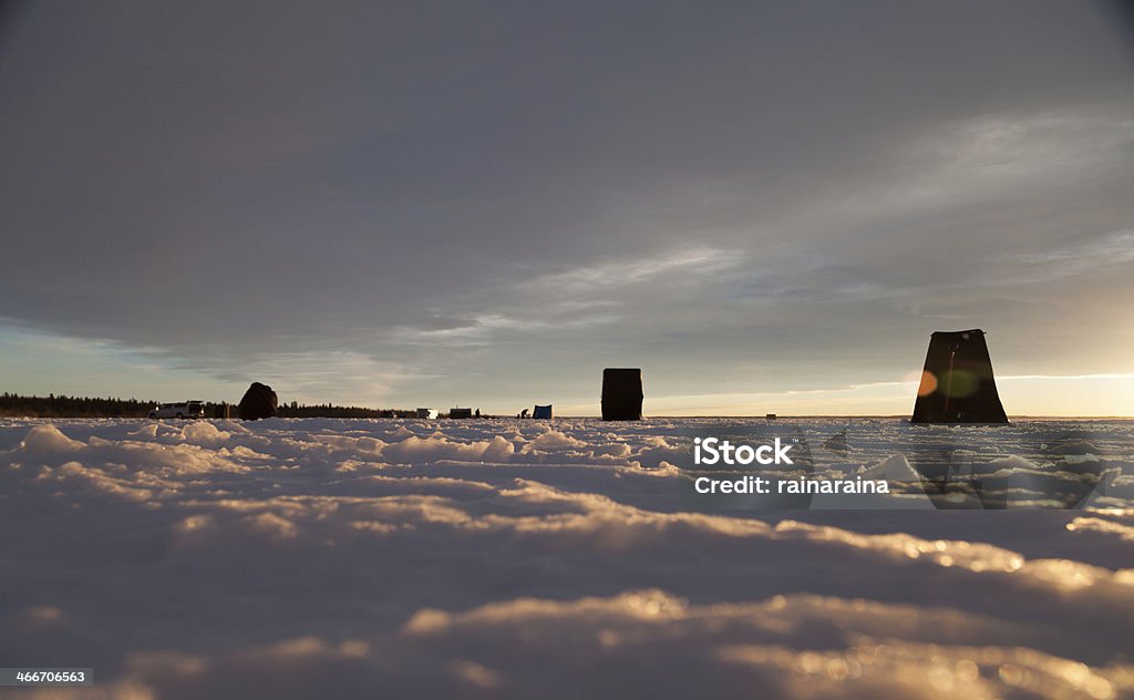 Ice fishing scene Black ice fishing tents across a frozen lake at sunset. Ice Fishing Stock Photo