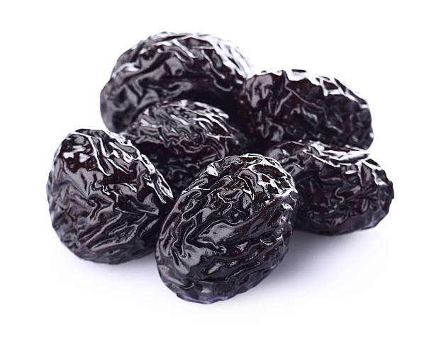 Several dried prunes on a white background stock photo