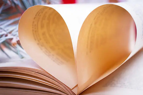 book.pages shapes heart on wooden background