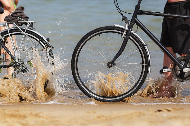 Sea wave splashing on the wheels of two bikes on the beach. Shallow depth of field.