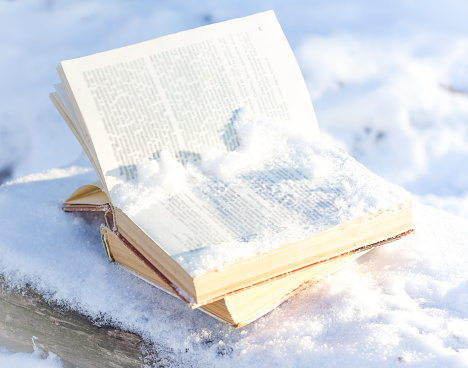 opened book under snow on winter background