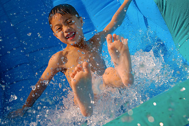 Headshot of a boy, 12 years old, having fun at a water park, a giant water slide out of focus behind him. He is grinning at the camera.
