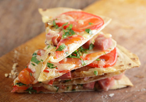 Tortilla pizza Stack of tortilla pizza slices on the wooden cutting board flatbread stock pictures, royalty-free photos & images