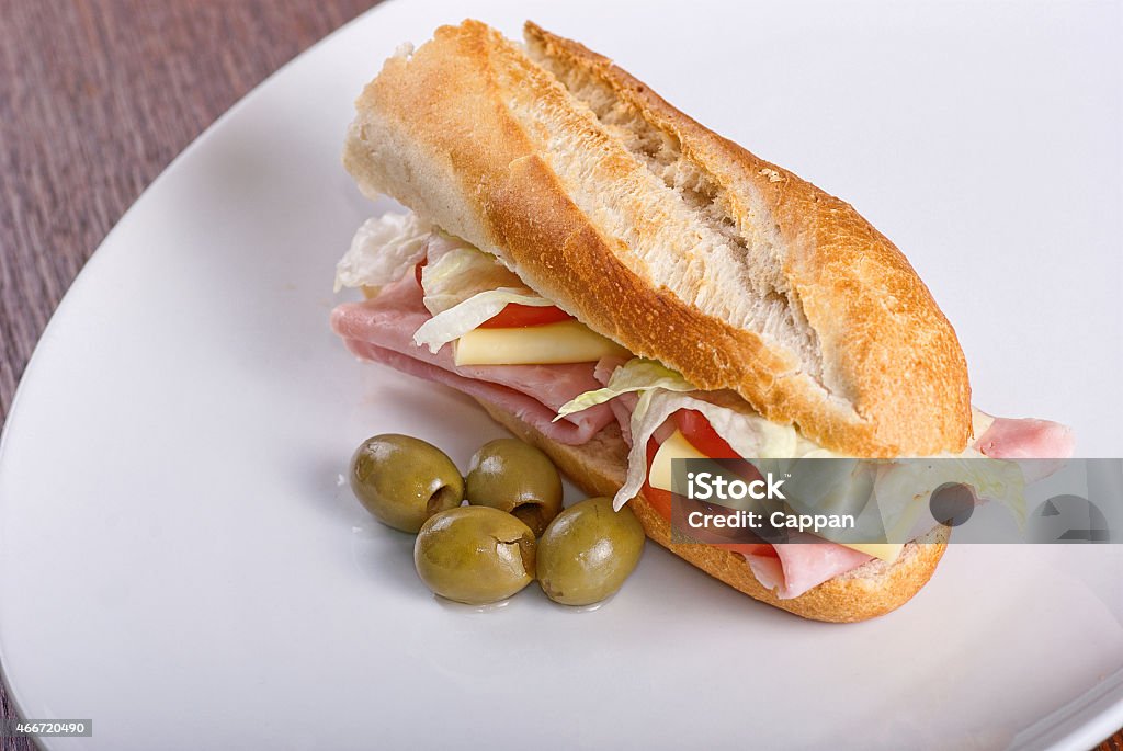 Homemade sandwich Homemade sandwich with ham, salad, cheese and tomatoes in white bread baguette on white plate 2015 Stock Photo