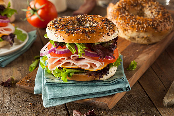 Healthy bagel with turkey and salad on a rustic table