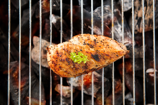 Marinated grilled chicken on the flaming grill.