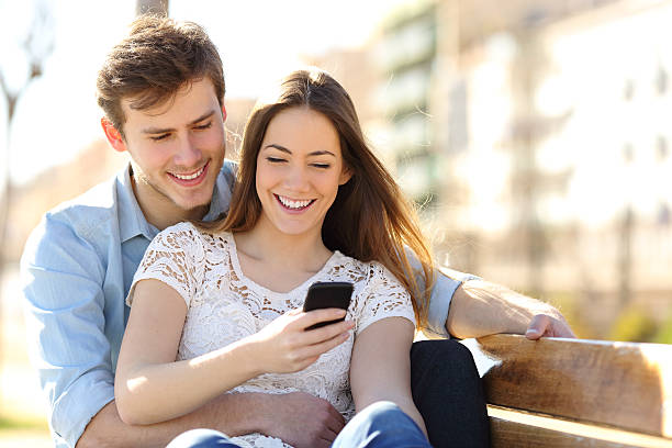 istock Couple sharing media in a smart phone in a park 466724774