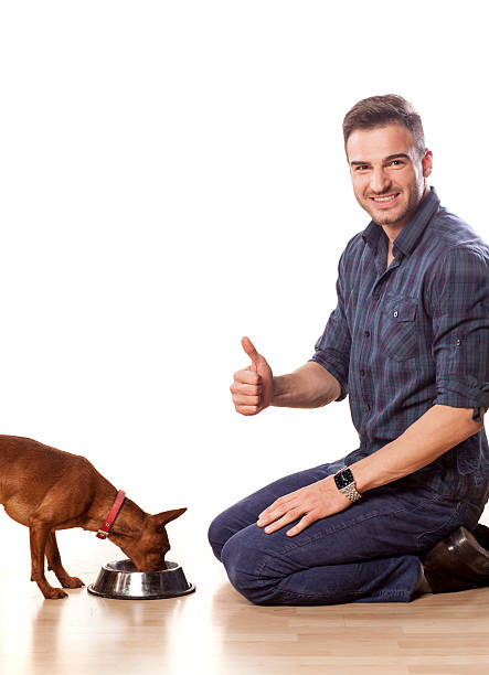 istock Young man feeding his dog and shows thumbs up 466724778