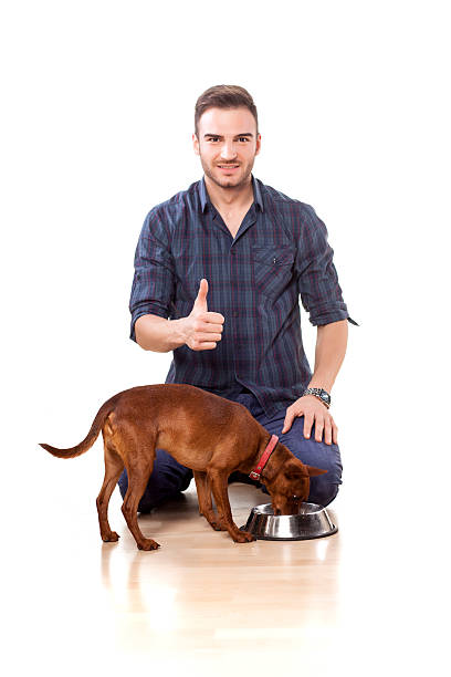 istock Young man feeding his dog and shows thumbs up 466724792