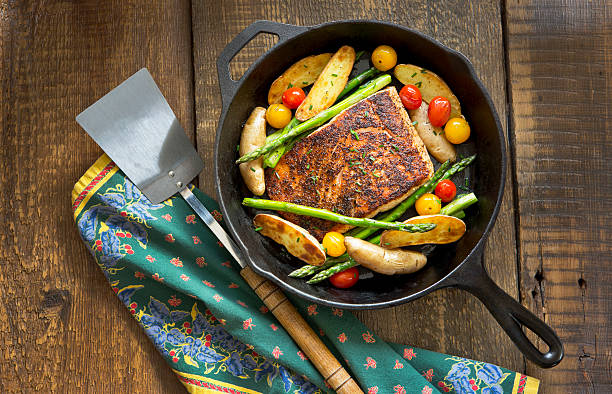 salmone arrosto e verdure in padella di ghisa. - salmone arrosto foto e immagini stock