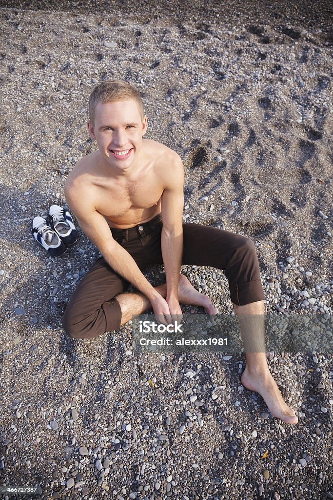 Young man relaxing at the beach, smiling at camera 20-29 Years Stock Photo