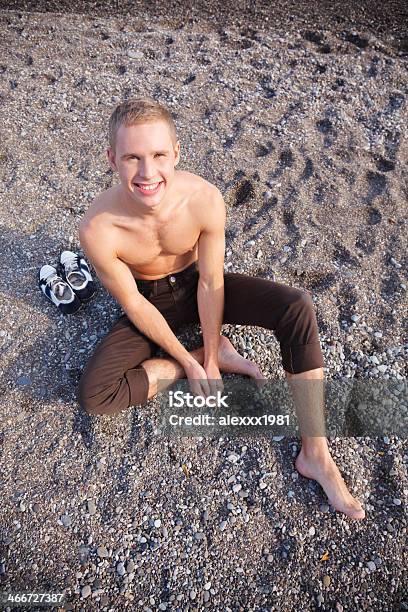 Young Man Relaxing At The Beach Smiling At Camera Stock Photo - Download Image Now - 20-29 Years, Adult, Adults Only