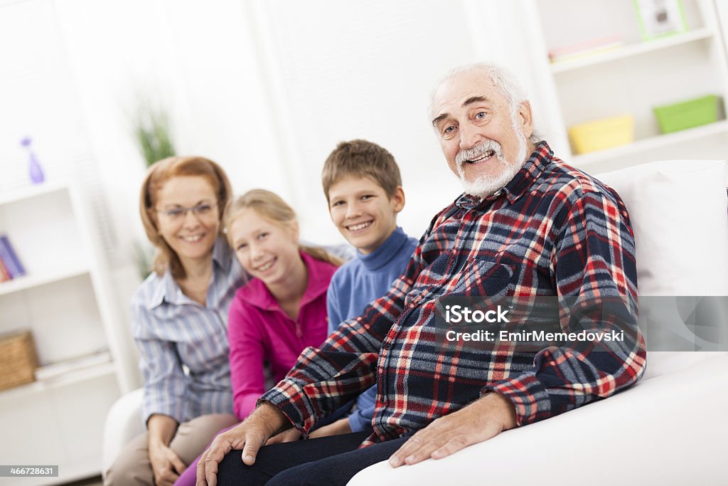 Grandparents with their grandchildren smiling at camera Grandparents with their grandchildren smiling at camera. Happy family , posing in casual clothing in living room. 60-69 Years Stock Photo