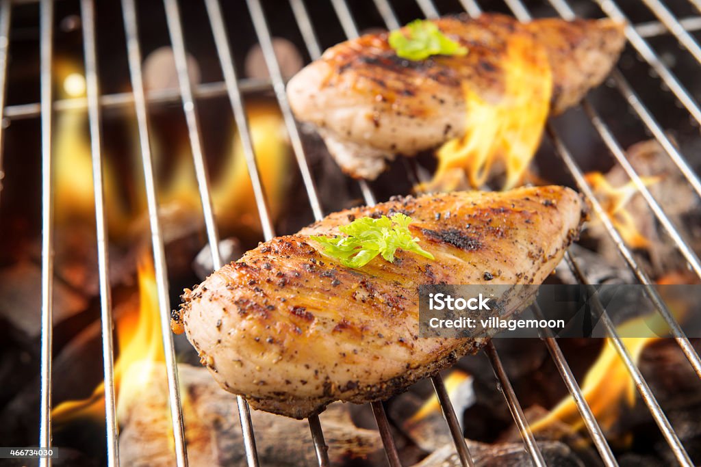 Marinated grilled chicken on the flaming grill Marinated grilled chicken on the flaming grill. Chicken Breast Stock Photo