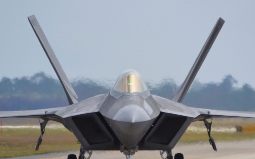 Head-on view of an F-22 fighter jet taxiing down the runway.