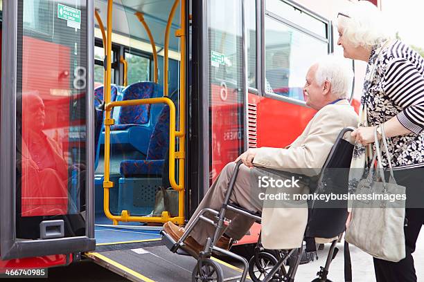 Photo libre de droit de Couple Senior Montant Dans Le Bus Avec Bretelle Daccès Pour Fauteuils Roulants banque d'images et plus d'images libres de droit de Bus