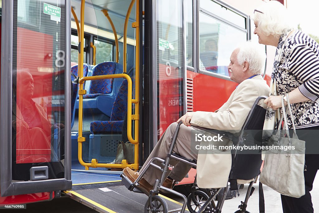Coppia Senior imbarco autobus utilizzando la rampa di accesso per sedia a rotelle - Foto stock royalty-free di Autobus