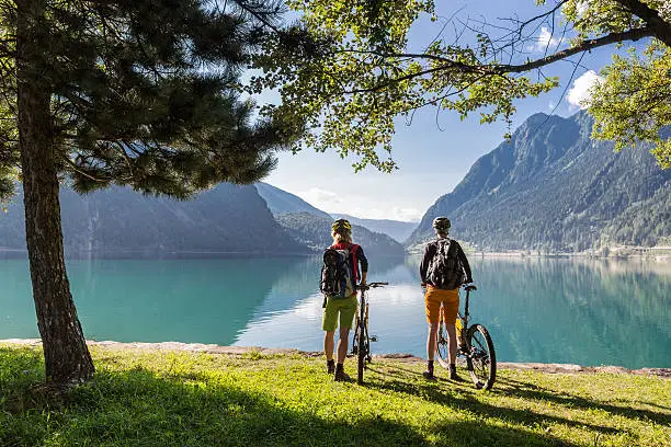 Two female Mountainbikers are taking a brake at lake Poschiavo, which is a natural lake in the Poschiavo valley.Poschiavo is a municipality in the district of Bernina in the canton of Graubünden in Switzerland.