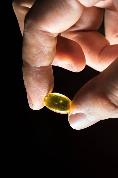 tirando omega 3 óleo de peixe cápsula. - capsule pill lecithin fish oil - fotografias e filmes do acervo