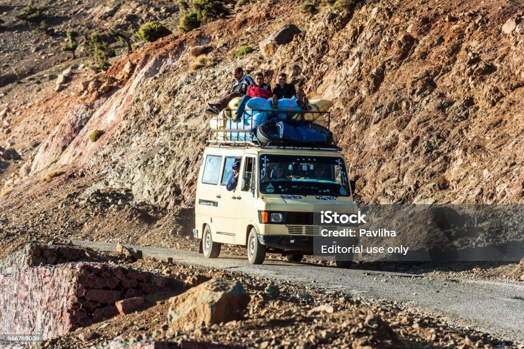 Full van on a mountain road Ait Tamlil ,Atlas Morocco Ait Tamlil,Morocco   - April 4, 2014: Full van on a mountain road in the Atlas Mountains Pass,Ait Tamlil,people on the roof of the car Morocco North Africa,Nikon D3x 2015 Stock Photo