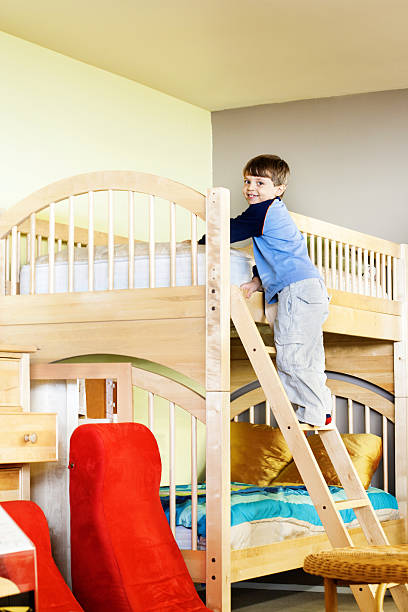 garoto escalando escada de madeira com um beliche de quarto infantil - mm1 - fotografias e filmes do acervo