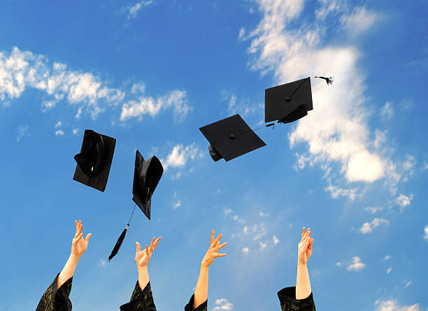 istock graduates throwing graduation hats in the air. 466757840