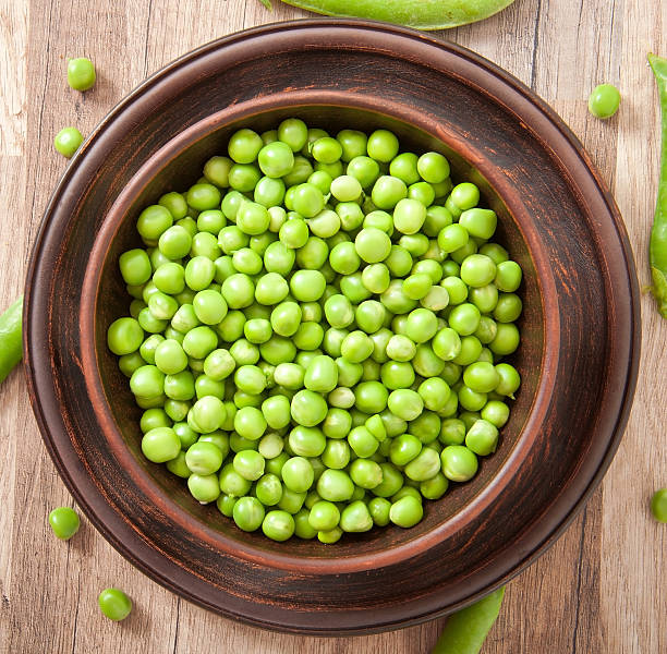 istock Green peas in a ceramic bowl on old wooden background 466764685
