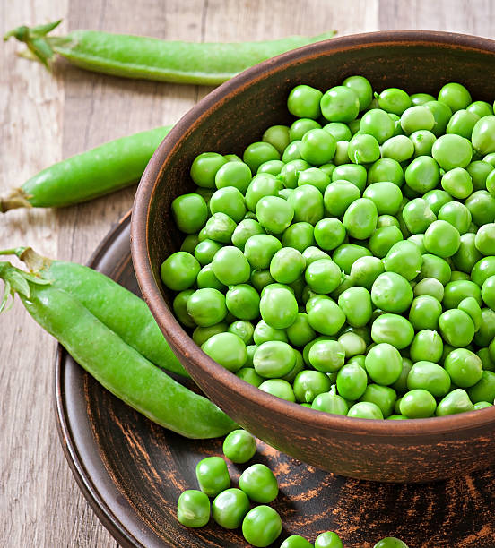 istock Green peas in a ceramic bowl on old wooden background 466765271