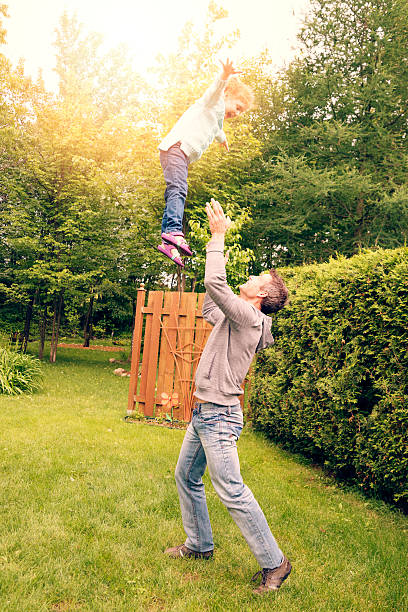istock Dad throwing kid in the air, suburban backyard. 466771483