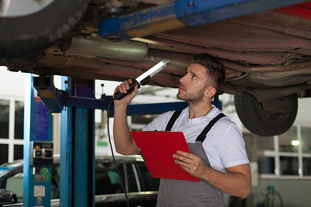 Young mechanic underneath a car inspecting the chassis