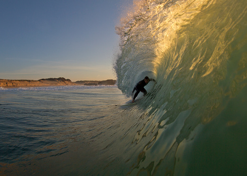 surfer getting barreled in afternoon light