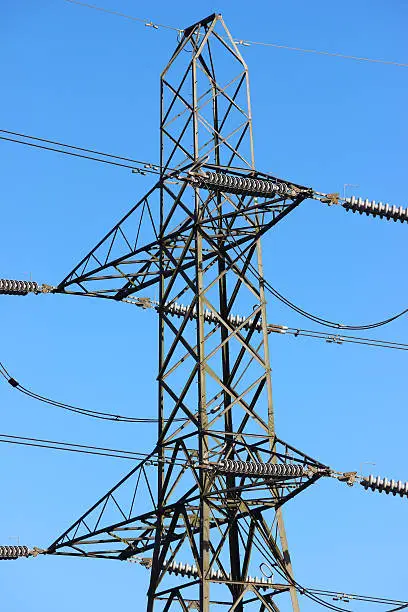 Photo showing a tall high-voltage transmission tower, which is known in the UK and much of Europe as an electricity pylon.  The photo shows a section of the tower, with wires, conductors and insulator strings.  This top part of the structure is named the 'peak', while the section beneath is the 'cage', complete with 'crossarms'.