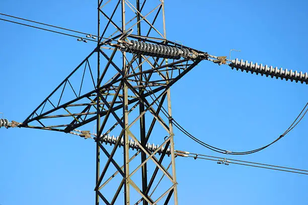 Photo showing a tall high-voltage transmission tower, which is known in the UK and much of Europe as an electricity pylon.  The photo shows a section of the tower, with wires, conductors and insulator strings.  This part of the structure is close to the top (peak) and known as the 'cage', with the 'crossarms' showing.