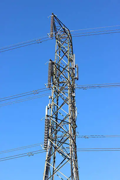 Photo showing a tall high-voltage transmission tower, which is known in the UK and much of Europe as an electricity pylon.  The photo shows a section of the tower, with wires, conductors and insulator strings.  This top part of the structure is named the 'peak', while the section beneath is the 'cage'.