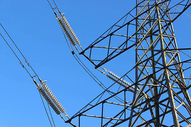 Photo showing a tall high-voltage transmission tower, which is known in the UK and much of Europe as an electricity pylon.  The photo shows a section of the tower, with wires, crossarms, conductors and insulator strings.  This part of the structure is close to the top (peak) and known as the 'cage'.