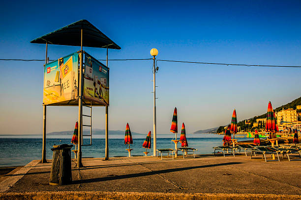 Opatija, Croatia - July 4, 2012: View of an empty lifeguard tower overlooking deserted beach loungers and umbrellas at sundown in the Croatian vacation resort of Opatija on the Gulf of Kvarner in the Adriatic