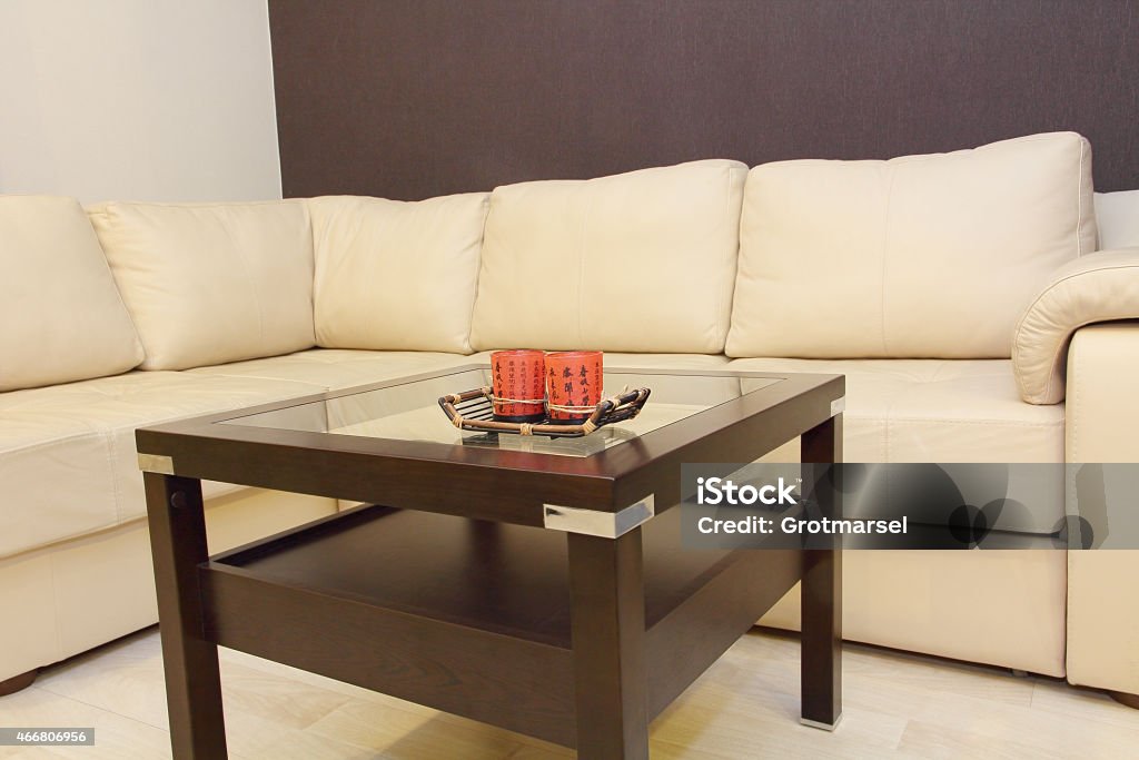 Coffee table and comfortable white corner leather sofa. Coffee table and comfortable white corner leather sofa in room. 2015 Stock Photo