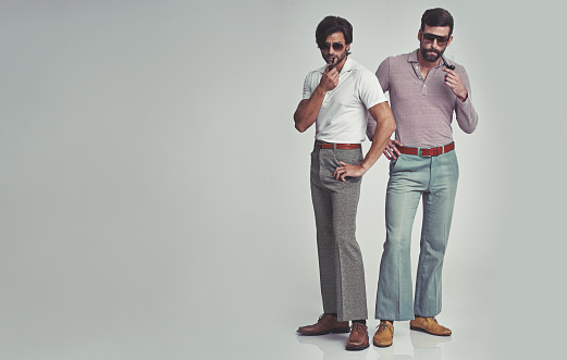 Studio shot of two men standing together while wearing retro 70s wear and smoking pipeshttp://195.154.178.81/DATA/i_collage/pi/shoots/782690.jpg