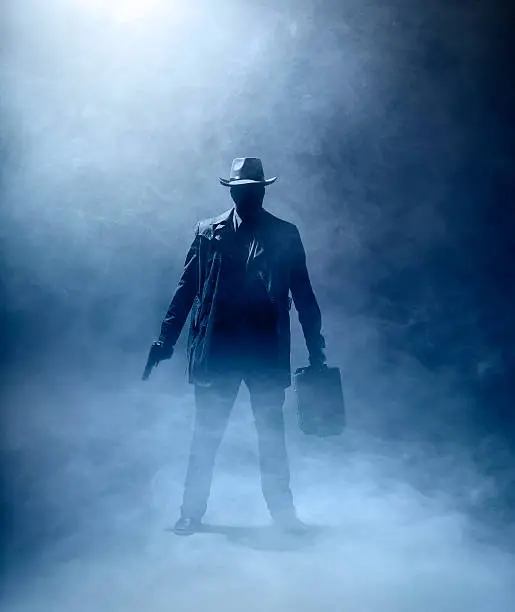 Faceles man with a gun and a briefcase standing in the fog.