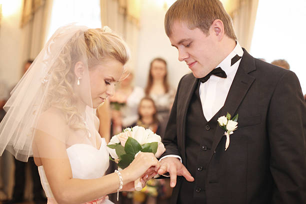 istock bride and groom wear a ring 466819428