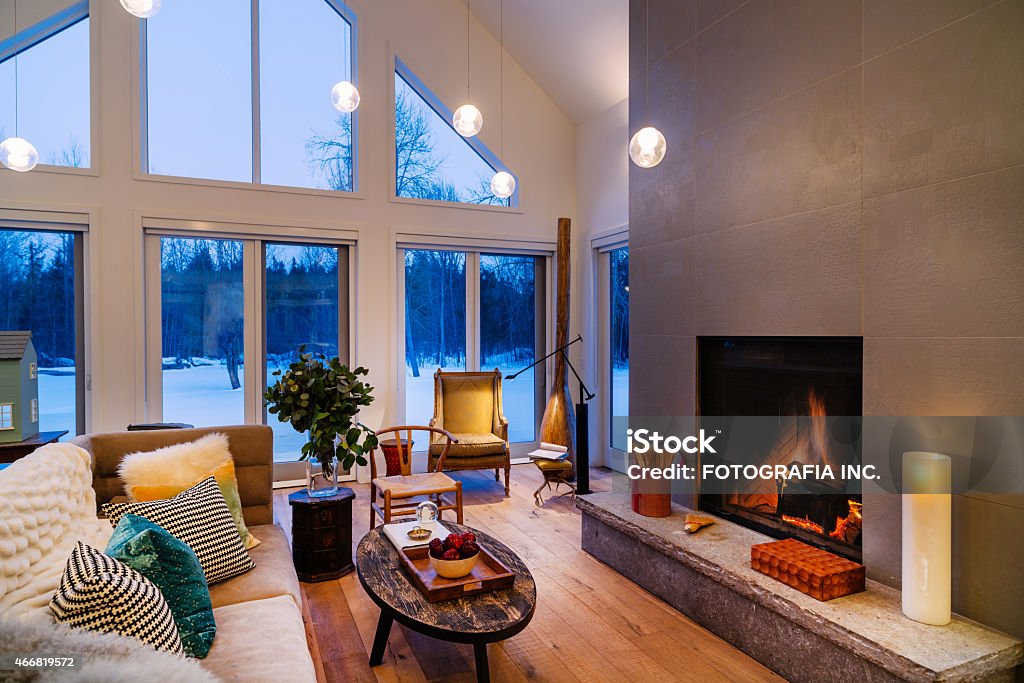 Collingwood Cottage Open Concept Interior North American Cottage interior. Main floor open area of winter home North of Toronto, Canada. Featuring large windows with view of surrounding area, grand fireplace and  modern mix of furniture and fabrics from around the world. Cottage Stock Photo