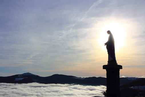 Statue of the Virgin above the fog in Alsace