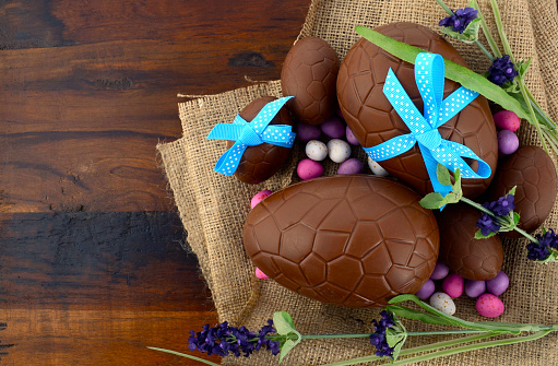 Happy Easter chocolate Easter eggs on dark wood country style table background.
