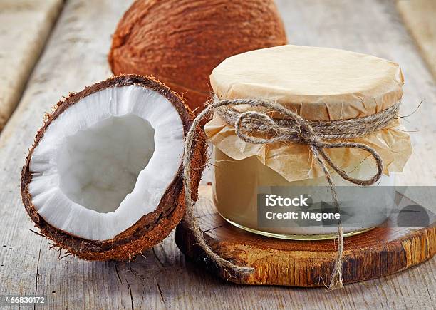 A Coconut Jar With Coconut Oil And Coconuts Sliced In Half Stock Photo - Download Image Now