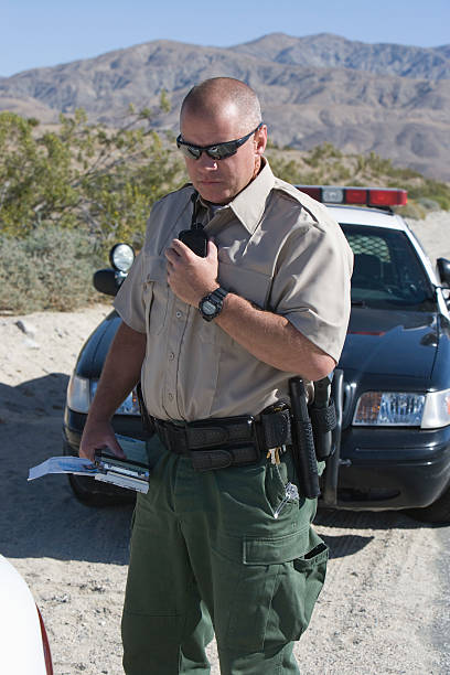 istock Policeman using walkie talkie near police car 466836074